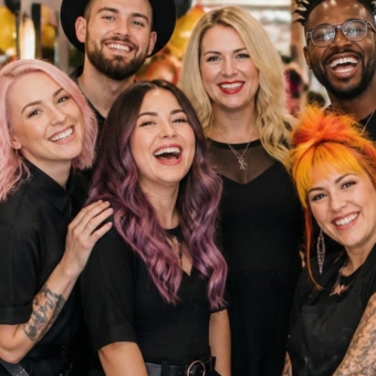 Group of six diverse young adults smiling in a celebratory manner