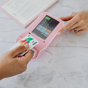 Person holding a credit card over a pink card reader