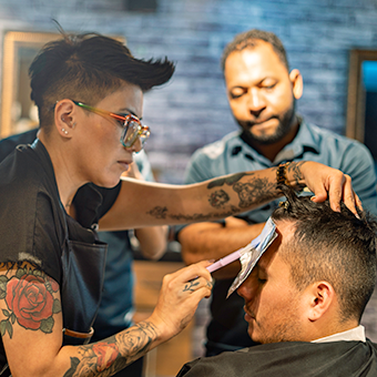 Cosmetology instructor applies foils to customer's hair while student observes