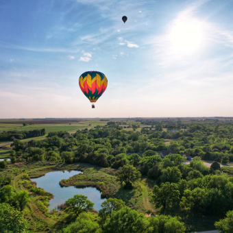 Photo of hot air balloon in the blue sky floating over green plains