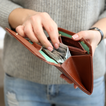 Woman sifting through bills in a brown leather wallet