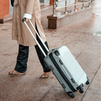 Person wheeling carry-on luggage in airport