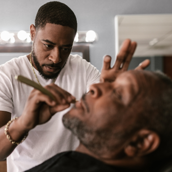 Barber using a straight razor to shave a client's beard