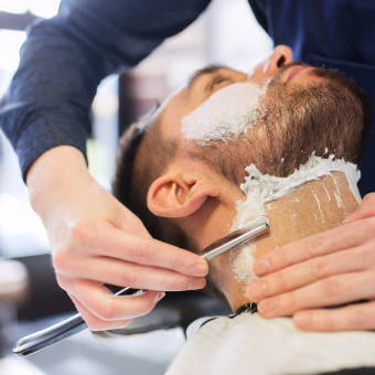 Bearded man receiving straight razor shave