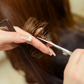 Woman holding shears and comb in her hands to trim brown hair