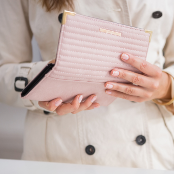 Woman in trench coat opening pink wallet